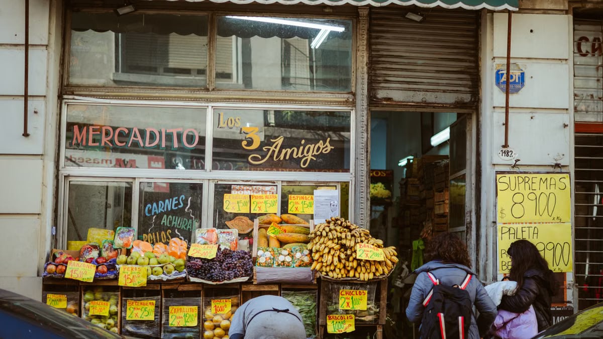 Street view of a local market 'Los Tres Amigos' in Buenos Aires with people shopping for fresh produce.