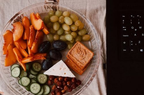 A delightful snack plate with fruits, cheese, and a laptop for a healthy lifestyle.